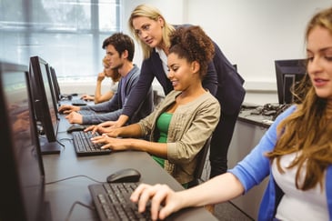 teacher helping students in a computer lab