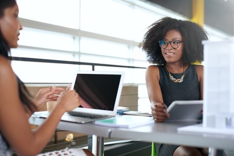 two women working on their laptops on a desk