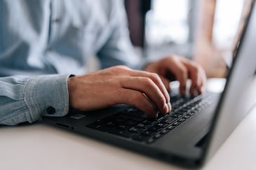 person sitting at a desk and typing on a laptop