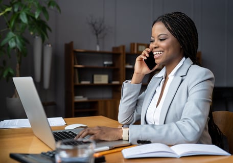 woman talking on the phone as she types on her laptop