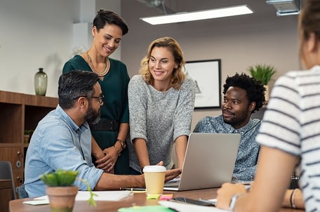 workers talking around a laptop