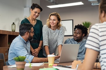 workers talking around a laptop